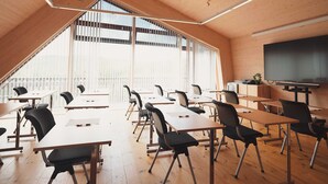 Una sala de conferencias moderna con suelos de madera y techos inclinados, ventanas amplias y un televisor de pantalla plana.