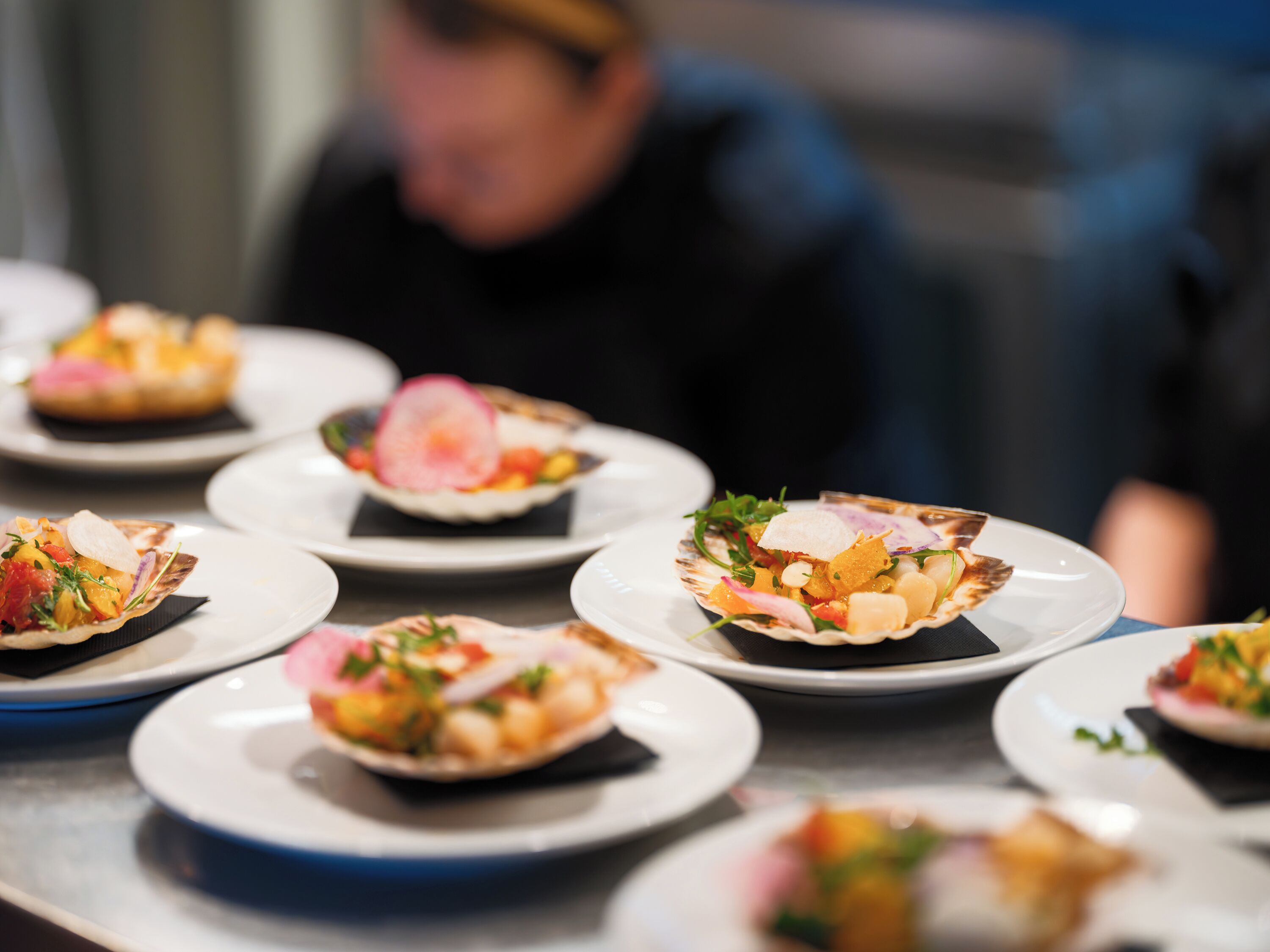 A table with plates of food, each containing a shell-shaped dish with various ingredients.