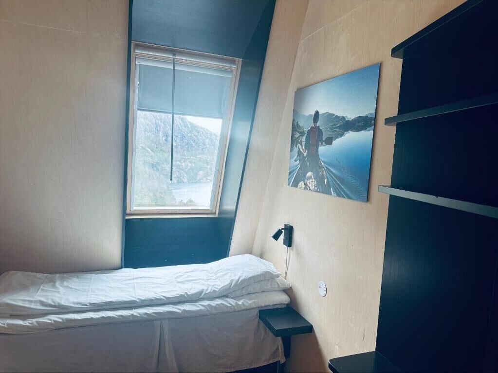 Une chambre à coucher avec un lit, une fenêtre, une étagère fixée au mur et un tableau.