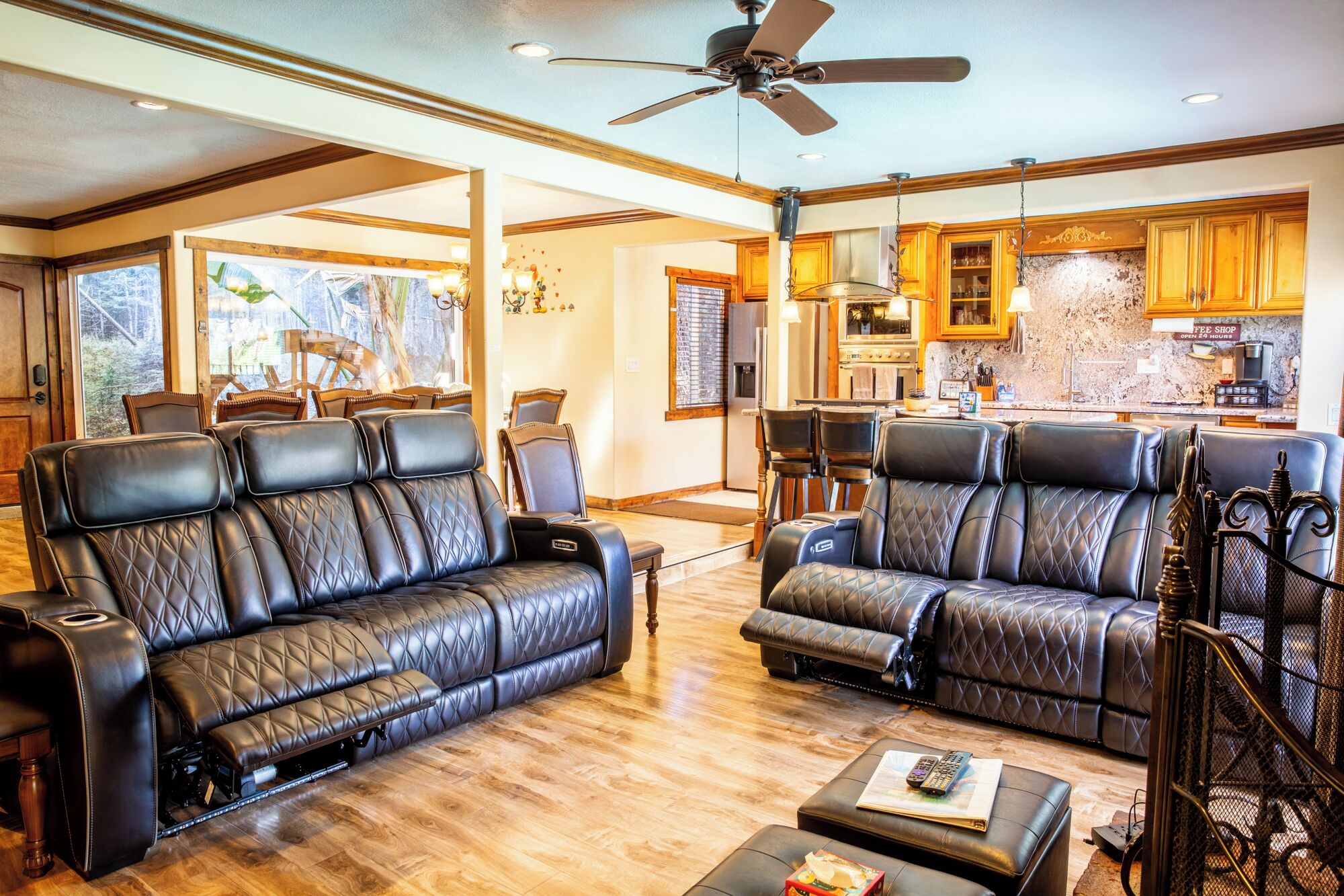 A living room with leather sofas, a coffee shop sign, and a kitchen in the background.