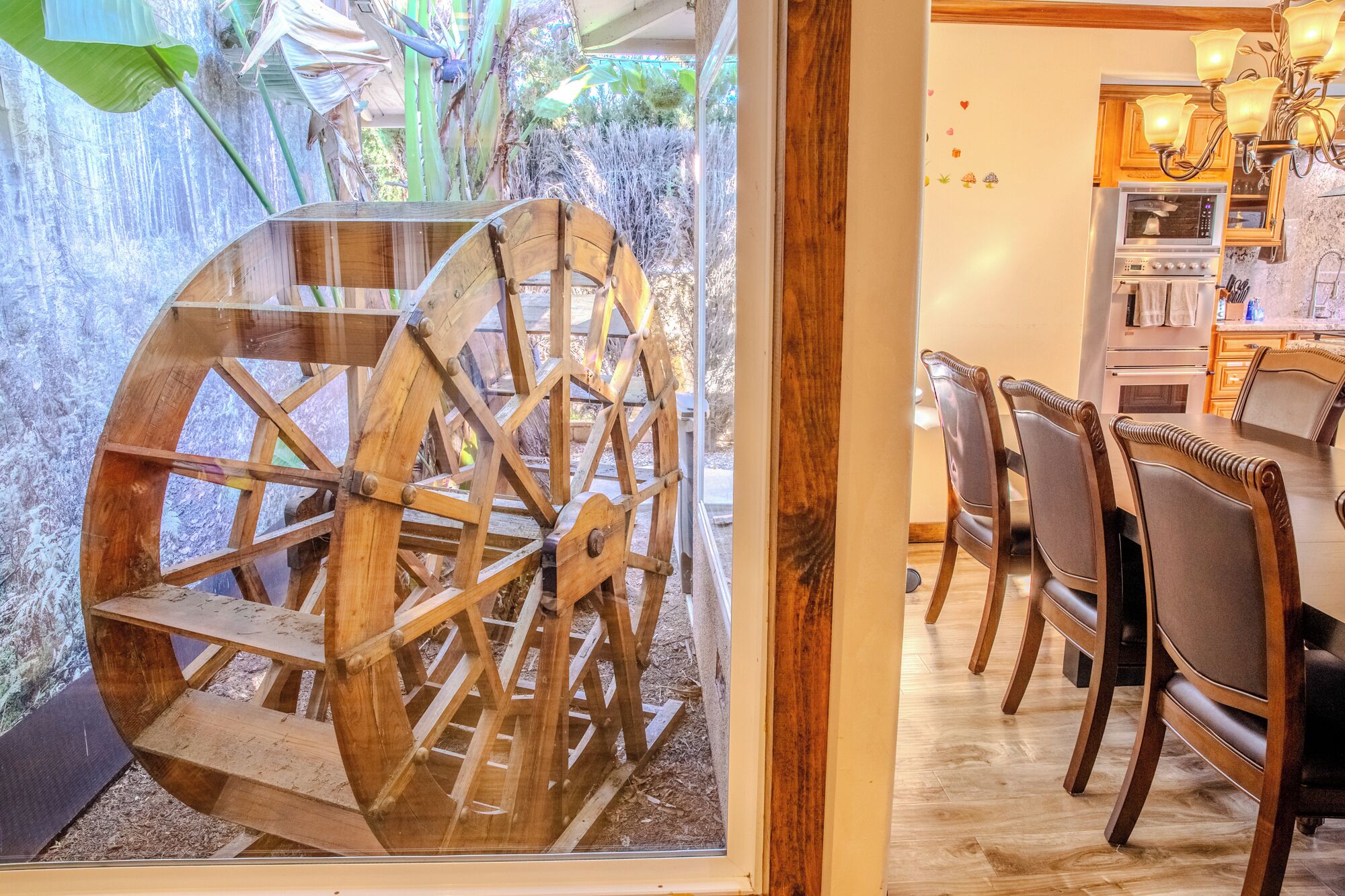 A rustic wooden water wheel, a dining area with wooden chairs, and a kitchen with wooden cabinets and a stove.