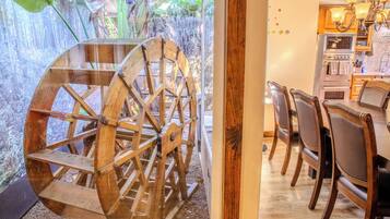 A rustic wooden water wheel, a dining area with wooden chairs, and a kitchen with wooden cabinets and a stove.