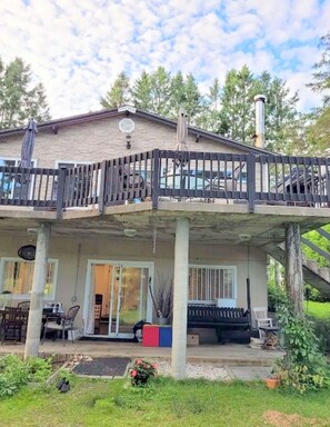 Une maison à deux étages dotée d’un patio couvert et d’une terrasse clôturée.