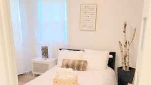 Ein Schlafzimmer mit einem großen Bett, einem Nachttisch, einer Wandlampe und einer Zimmerpflanze.