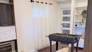 Ein Wohnzimmer mit einer Couch, einem Kicker, einem Glastisch, einem Kamin und einem Bücherregal.