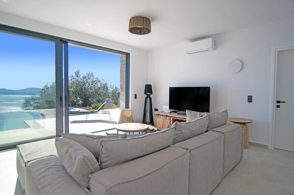 A modern living room with a large window, a flat-screen TV, and a sofa.
