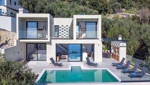 Et moderne hus i to etager med swimmingpool og udendørs siddeplads.