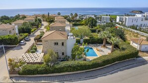 Un barrio residencial con edificios de piedra, una piscina y vista al mar.