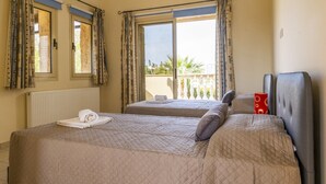 Habitación de hotel con dos camas, un radiador y vista a un balcón con plantas.