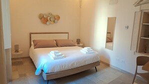 A bedroom with a bed, bedside tables, a wall-mounted light fixture, and a mirror.