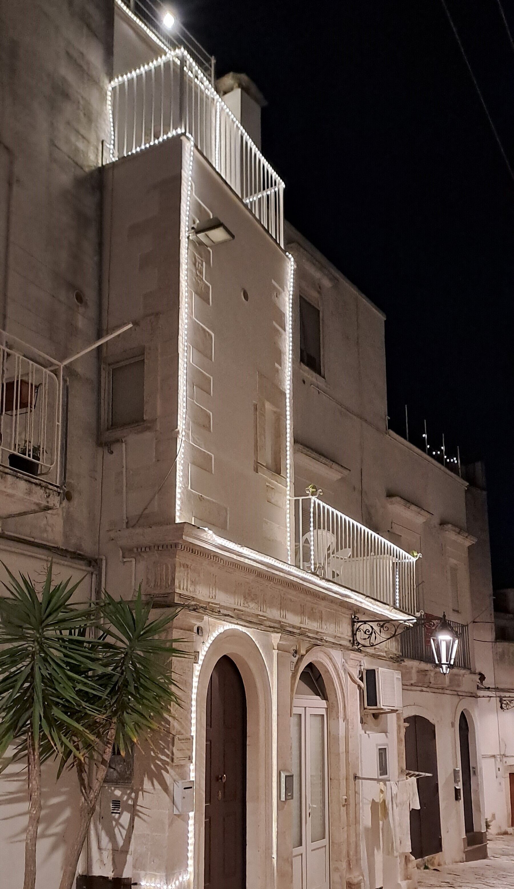 Un edificio histórico con un balcón, arcos y una palmera frente a él.