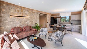 Una sala de estar moderna con una pared de piedra, un sofá, una mesa de centro y un comedor con sillas y una mesa.
