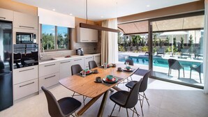 Una cocina moderna con comedor, ventanas amplias y vista a una piscina.