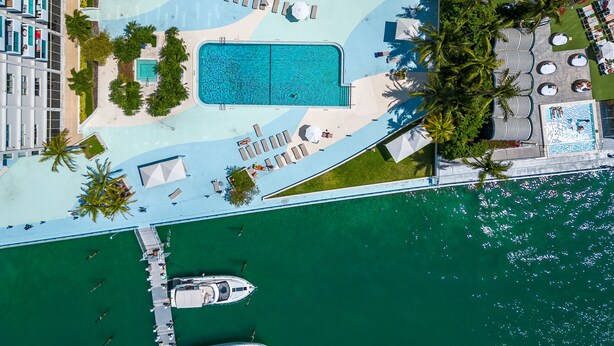An aerial view of a resort with a large swimming pool, sun loungers, and a marina with boats. - Best view in Miami Beach (Miami Beach)