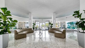 A spacious lobby with a marble floor, two beige sofas, and large potted plants. - Best view in Miami Beach (Miami Beach)