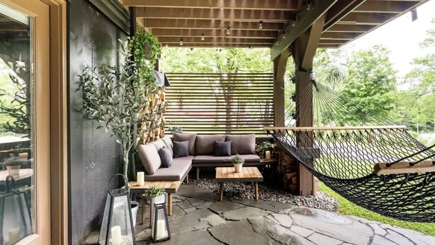An outdoor seating area with a cushioned sofa, a small table, and a hammock. - Entire Cabin - Modern A-Frame w/Hot Tub (Ellenville)