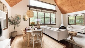 A cozy interior with a wooden ceiling, a dining area with a table and chairs, a sofa, and a fireplace. - Entire Cabin - Modern A-Frame w/Hot Tub (Ellenville)
