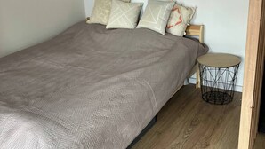 A bedroom with a bed, pillows, a round side table, and a dreamcatcher on the wall. - Soul Apartment In The Center (Szczecin)