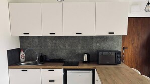 A compact kitchen with white cabinets, a built-in dishwasher, a coffee maker, and a toaster. - Soul Apartment In The Center (Szczecin)