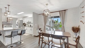 A modern kitchen with white cabinets, a central island with bar stools, and pendant lighting.