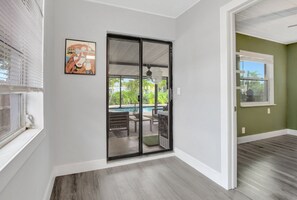 Ein Zimmer mit einer Schiebetür zu einer Außenpatio mit Pool, Deckenventilator und einem gerahmten Kunstwerk an der Wand.