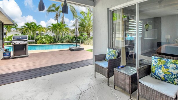 A covered patio with a pool, outdoor furniture, and a grill.