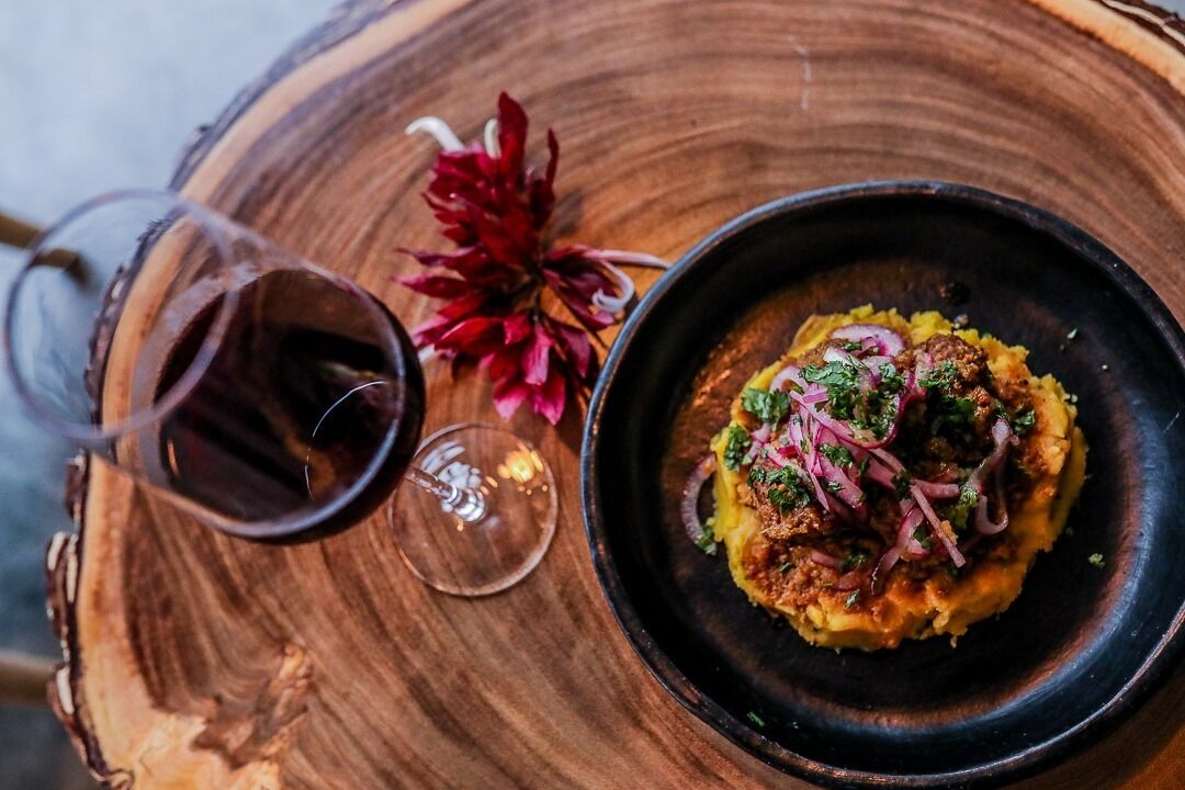 A plate of food with a glass of red wine on a wooden table.