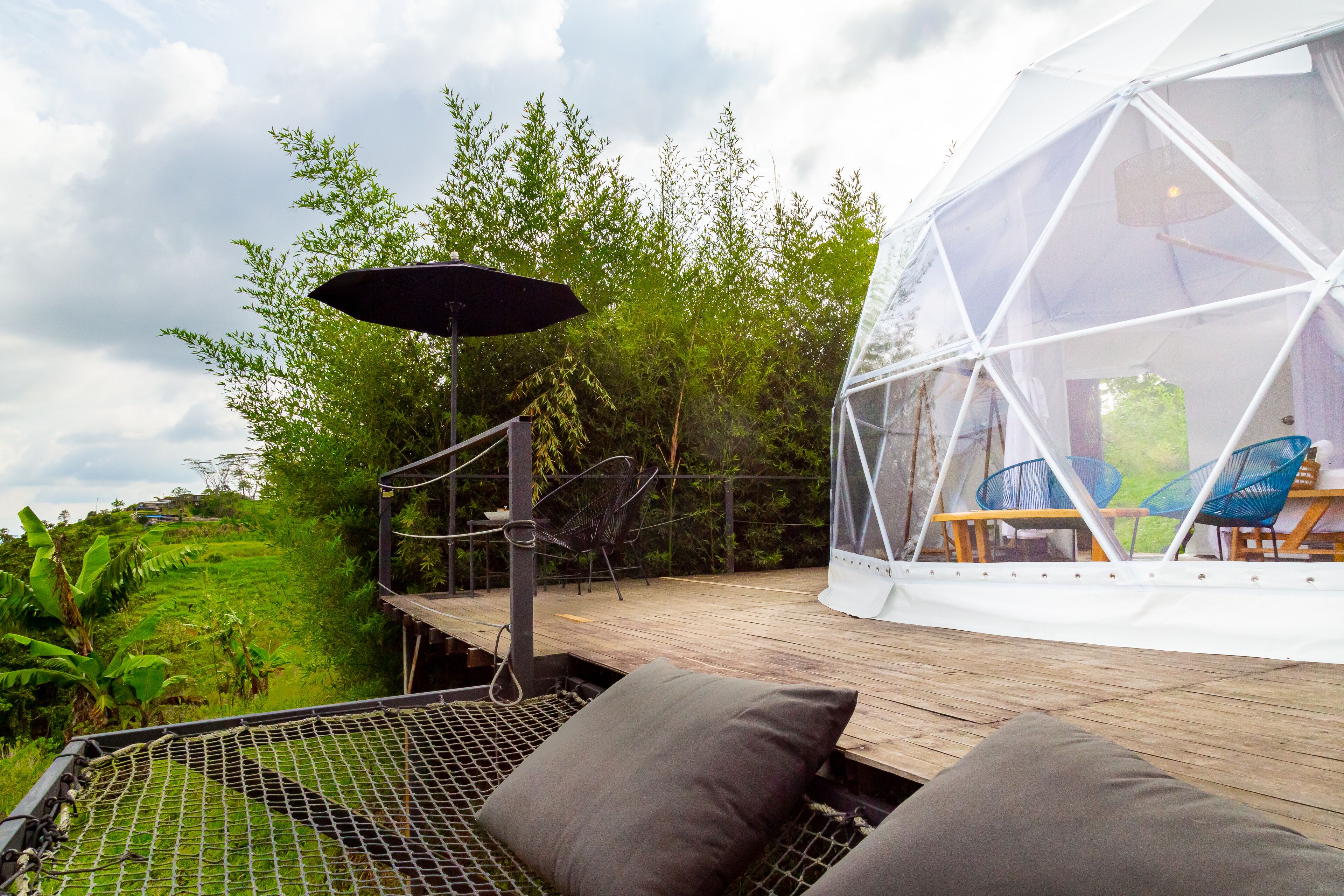 A transparent dome structure with a wooden deck and seating area.