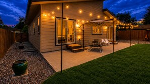Ein modernes Haus mit Terrasse, Gartenmöbeln und Lichterketten.