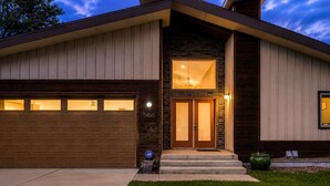 Ein modernes, zweistöckiges Haus mit Garage, Naturstein-Fassade und einer gut beleuchteten Eingangspartei.