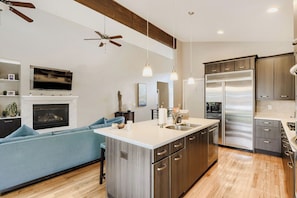 A modern kitchen with a central island, stainless steel appliances, and a built-in oven.