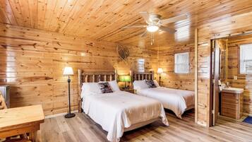 Une cabine équipée de deux lits, d’un ventilateur de plafond, d’un plancher en bois et d’une petite salle de bain.