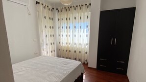 A bedroom with a bed, a wardrobe, and a ceiling light. - Albania Dream Holidays Accommodations (Sarandë)