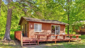 A wooden cabin with a porch, a table, and a bench. - Cabin #10 2BR 1BA Timberlane Resort (Park Rapids)