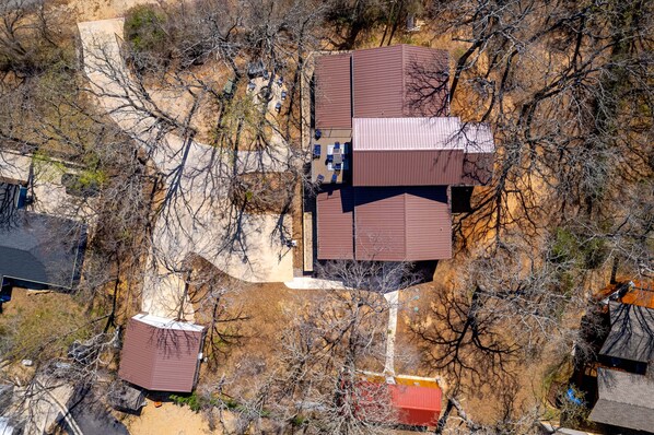 An aerial view of a residential area with multiple houses, including a central house with a brown roof and a visible patio area.