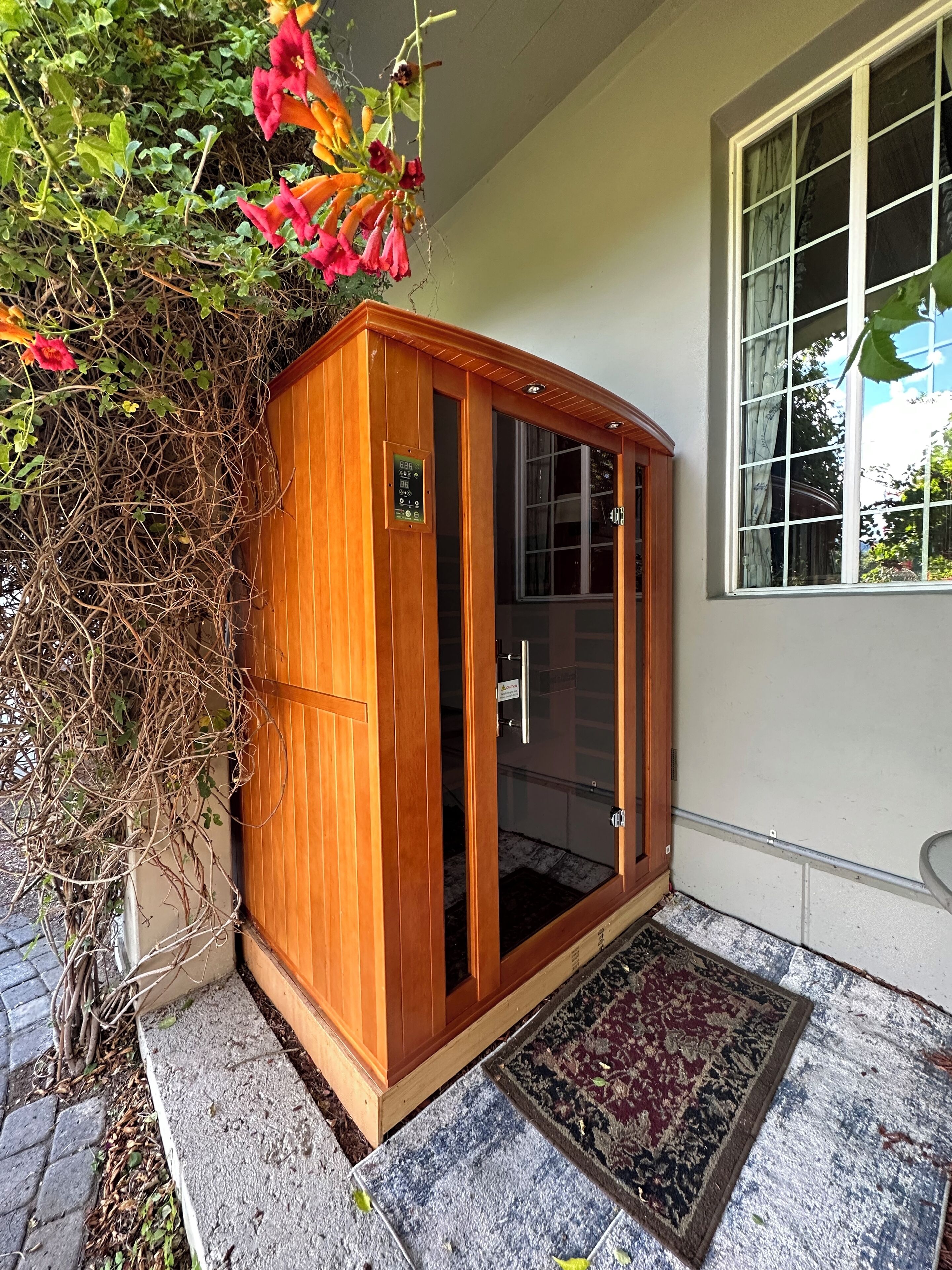 A wooden cabinet with a glass door, a small sign, and a rug on the ground.