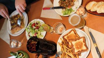 A dining table with various dishes, including a plate of French fries, a sandwich, and a salad. There are also drinks and utensils on the table.