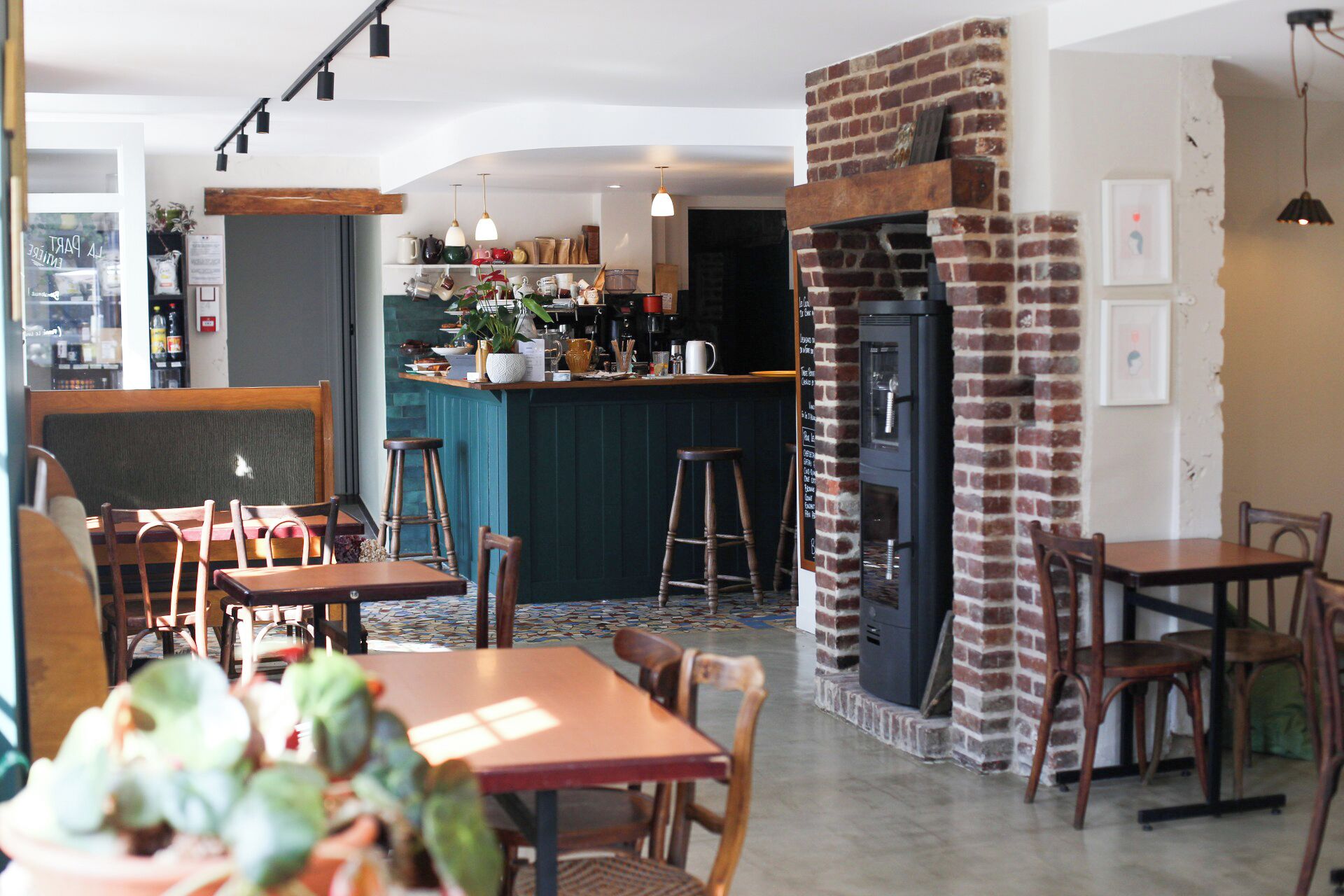 Un restaurante acogedor con chimenea de ladrillo, mobiliario de madera y una zona de bar con estantes llenos de botellas y vasos.