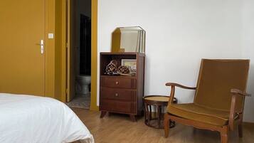 A room with a bed, a wooden dresser, a chair, and a small table.