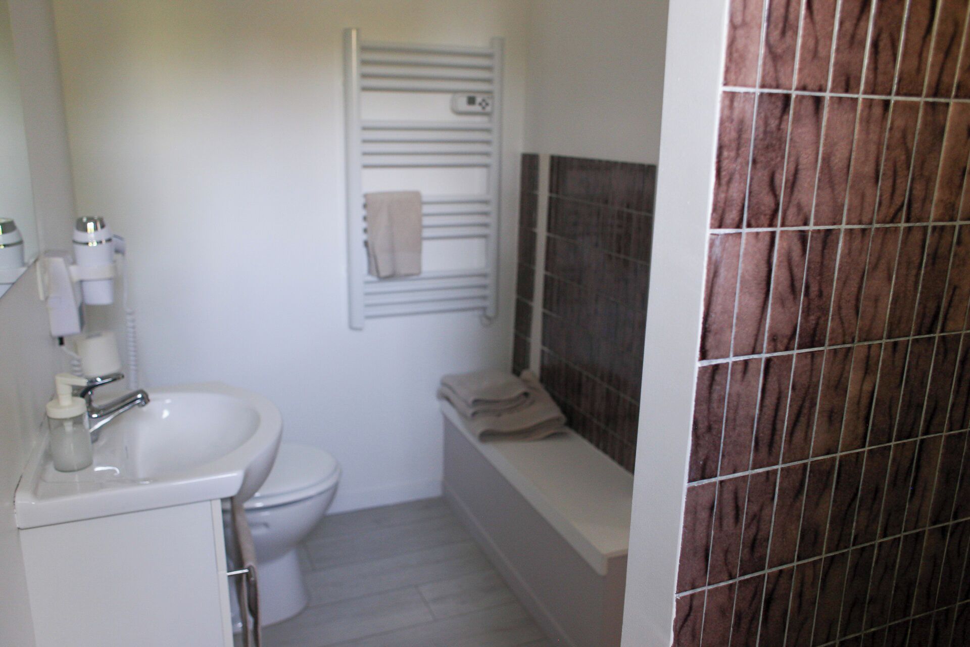 A bathroom with a white sink, toilet, and a bathtub with a towel on the edge.