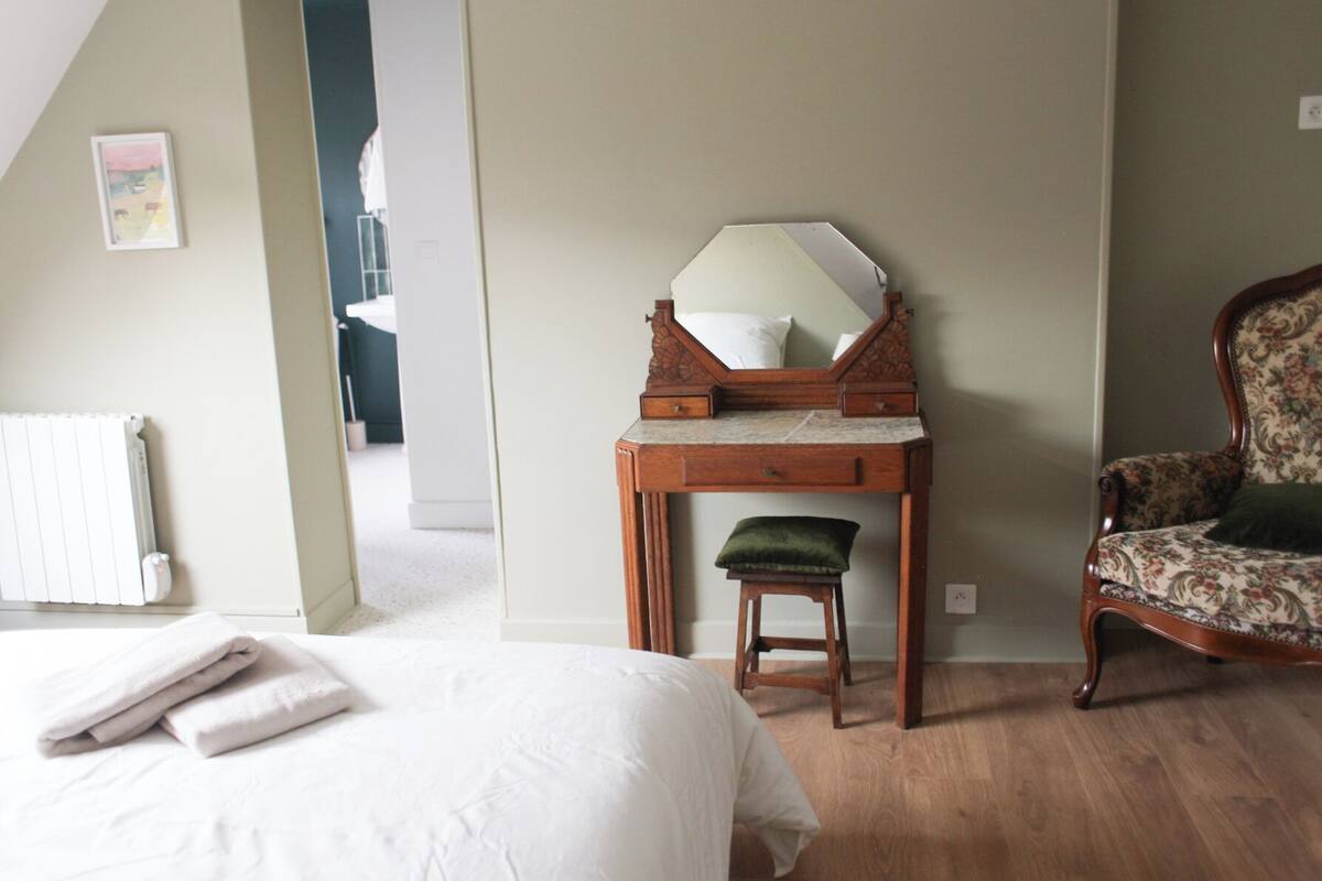 Une chambre à coucher avec un lit, un bureau en bois doté d’un miroir, une chaise et un radiateur.