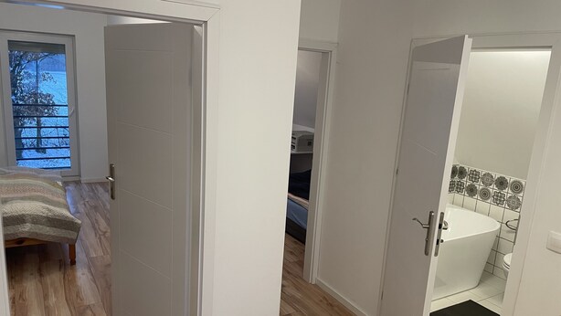 Un dormitorio moderno con una cama, piso de madera y vistas al exterior.