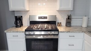 A kitchen with white cabinets, a stainless steel stove, and a tiled backsplash. - Cozy Country Living, just outside the city of Lubbock.  (Shallowater)