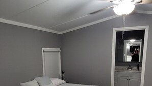 A bedroom with a bed, a ceiling fan, a mirror, and a door. - Cozy Country Living, just outside the city of Lubbock.  (Shallowater)