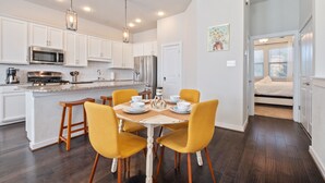 A modern kitchen with white cabinets, a central island, and yellow chairs. - Chic 3-Bed Condo, 2-Car Garage close to Pearl & St. Mary's Strip in Tobin Hills! (San Antonio)