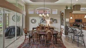A dining area with a round table, chairs, and a chandelier.