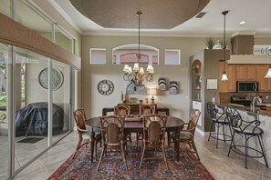 A dining area with a round table, chairs, and a chandelier.
