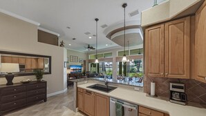 A spacious kitchen with a large island, wooden cabinets, and a built-in microwave.