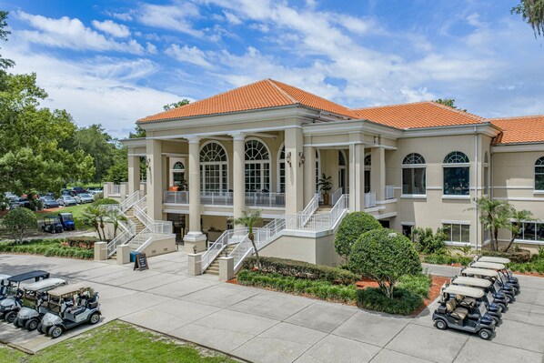 A hotel with a central courtyard, a covered outdoor seating area, and a parking lot with golf carts.