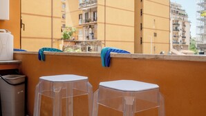 A balcony with two clear plastic stools, a trash bin, and a water dispenser.